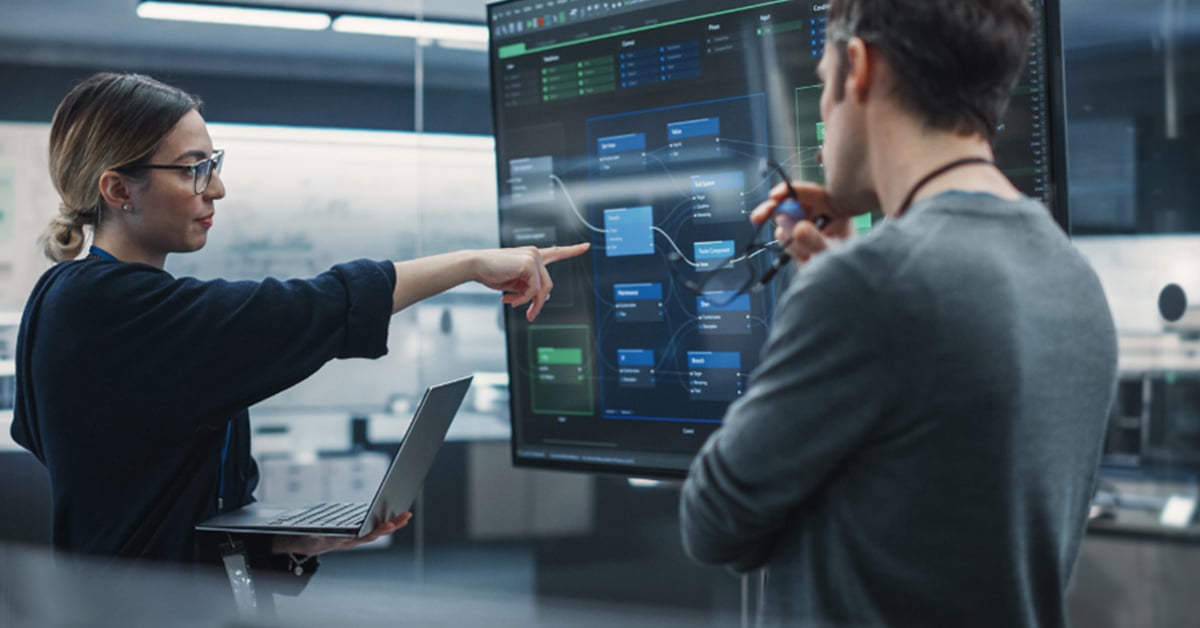 Deux membres d'une équipe de R et D qui discutent devant des écrans