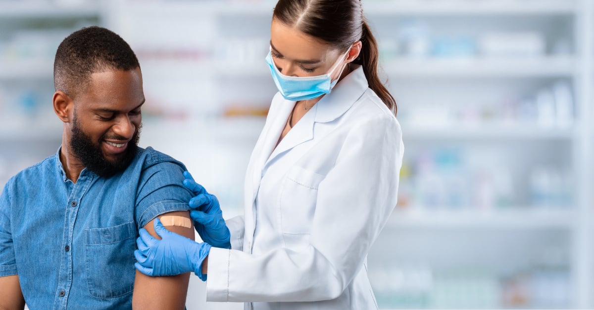 A pharmacist putting a bandage on the arm of a patient she just vaccinated.