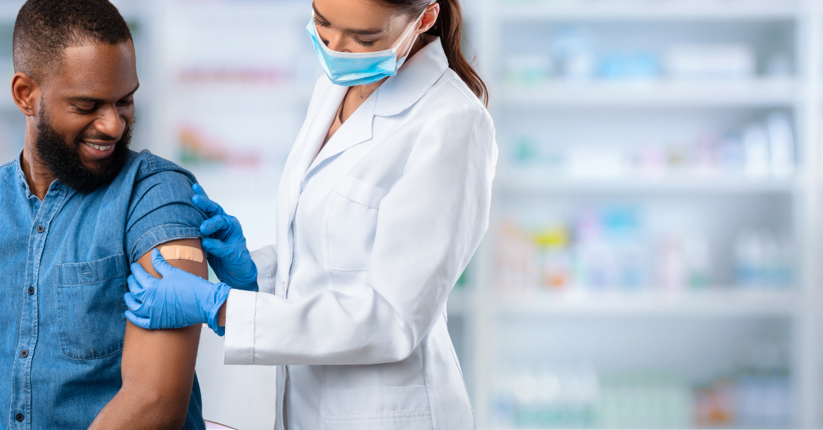 A pharmacist putting a bandage on the arm of a patient she just vaccinated.