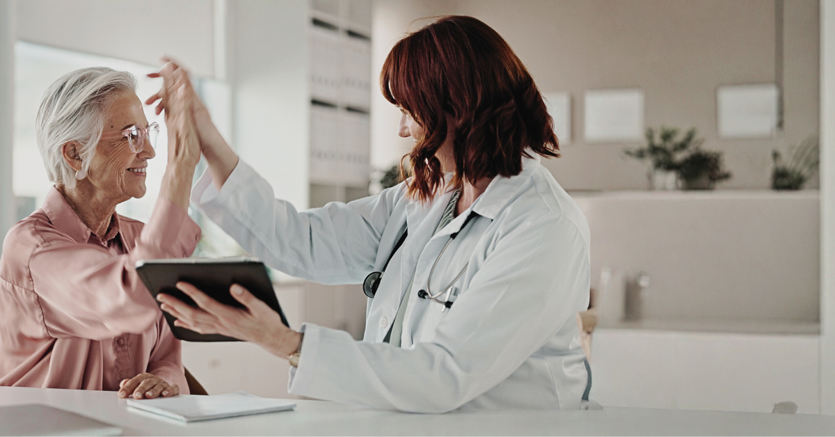 A female health professional giving a high five to an elderly female patient