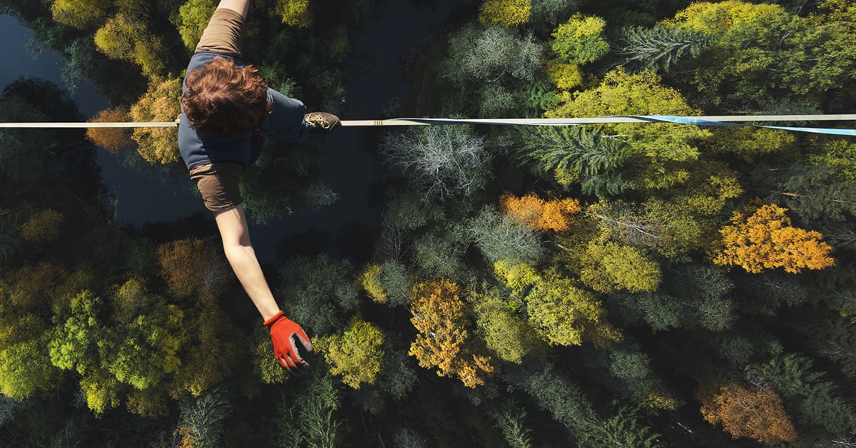 Un équilibriste qui marche sur un fil au-dessus d'une forêt